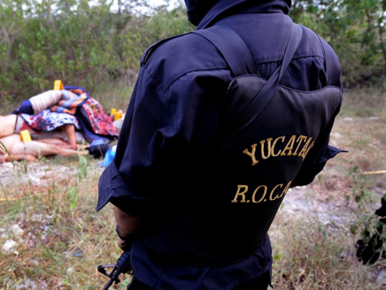 A police officer on Sunday keeps a perimeter around some of the 11 beheaded corpses found  in a suburb of Merida, Mexico.